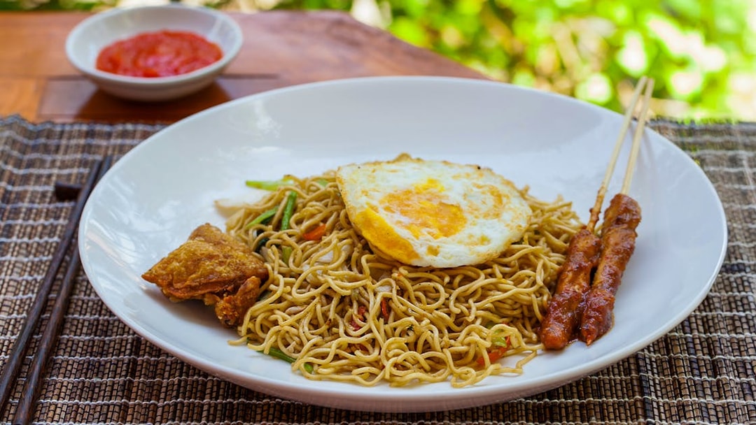 Nasi goreng with fried egg, satay skewers, and sambal, Ubud tour meal option.