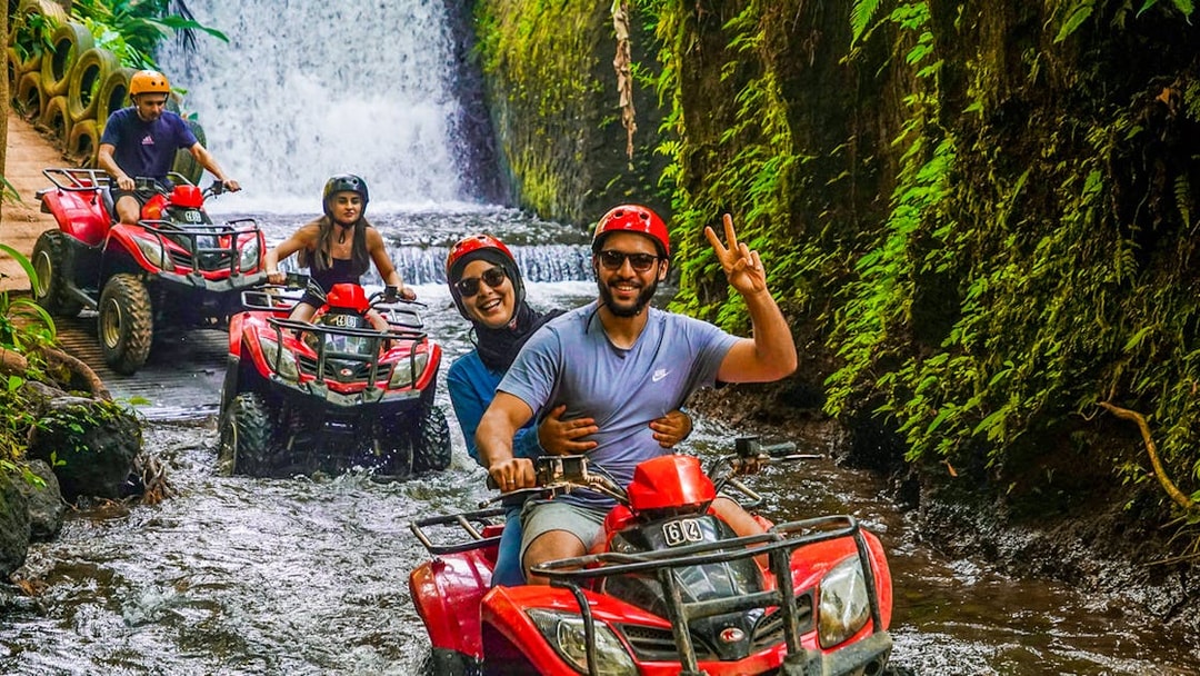 ATV riders navigating a jungle stream near Goa Raja Waterfall in Ubud.