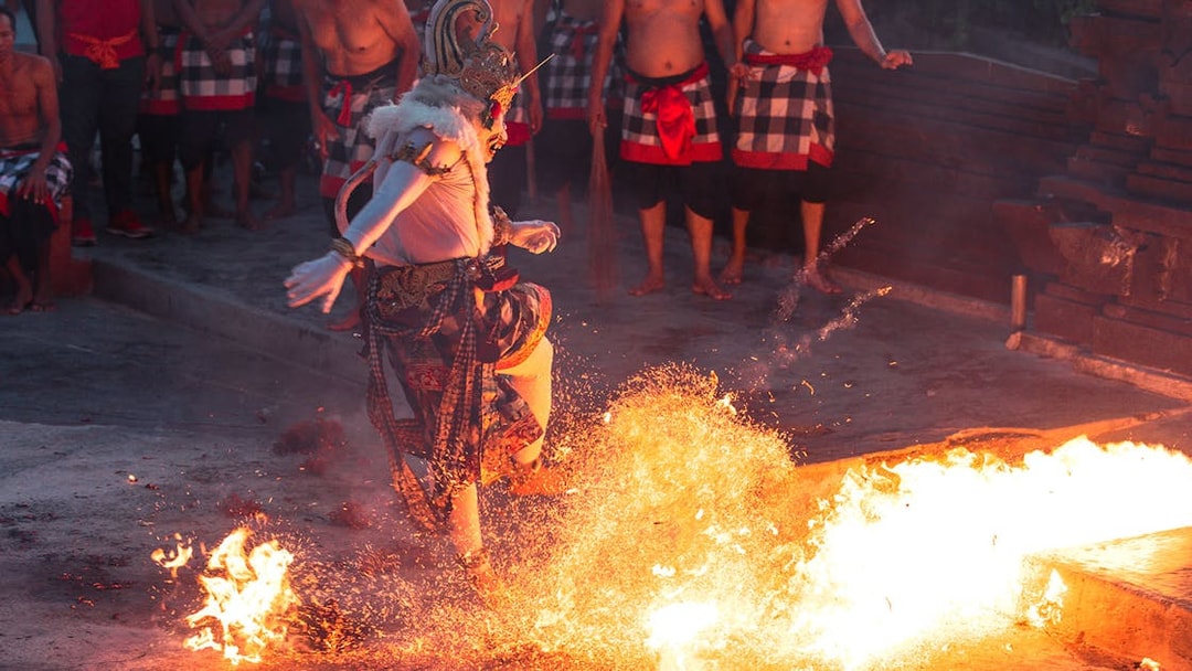 Performer in traditional costume dancing around fire at Ubud Kecak & Fire Dance Show.