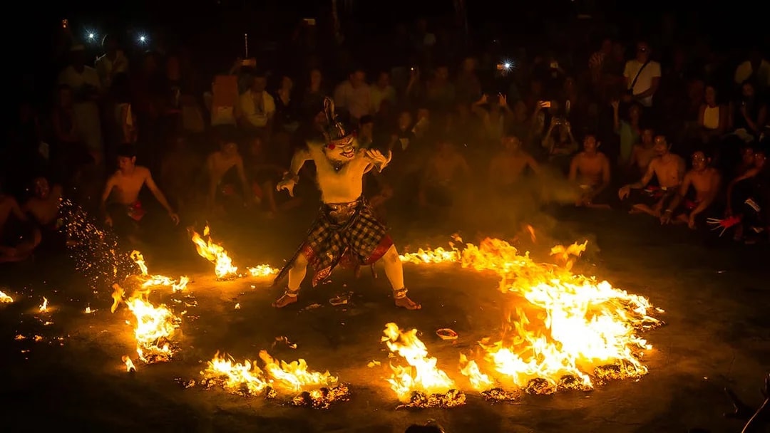 Performer in traditional costume surrounded by fire at Uluwatu Kecak & Fire Dance Show, Bali.