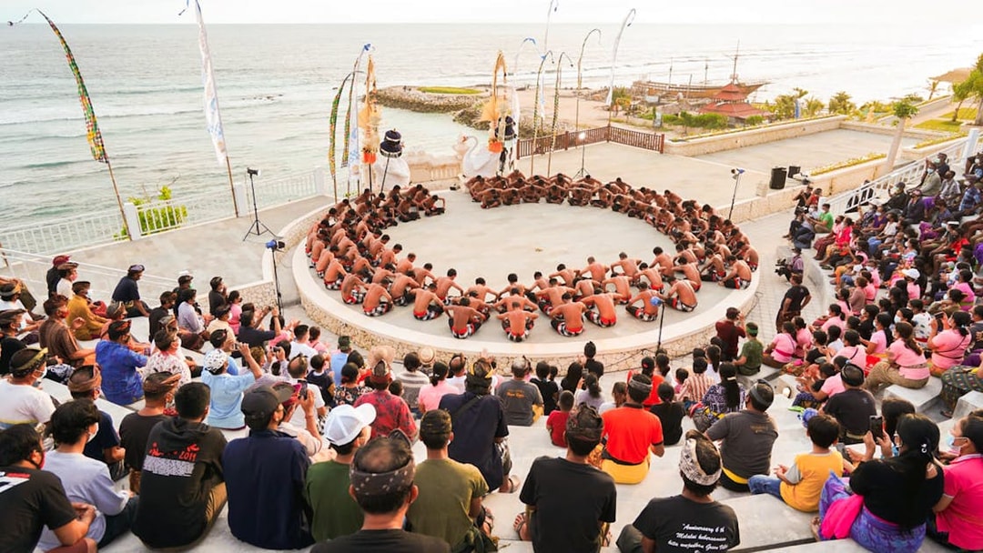 Kecak dancers performing in a circle at Ubud amphitheater with ocean view.