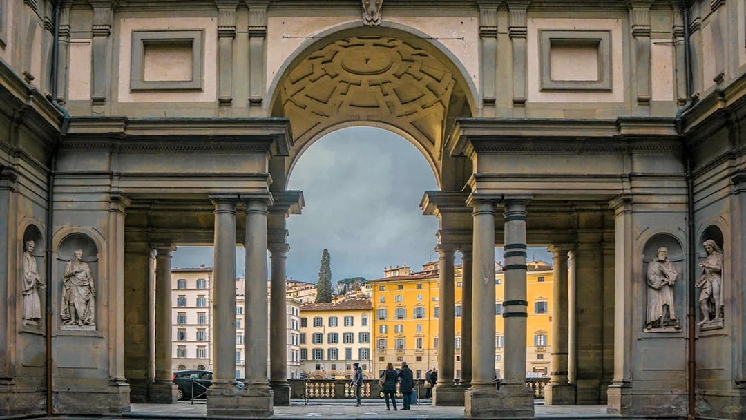 Uffizi Gallery entrance with statues and view of Florence buildings.