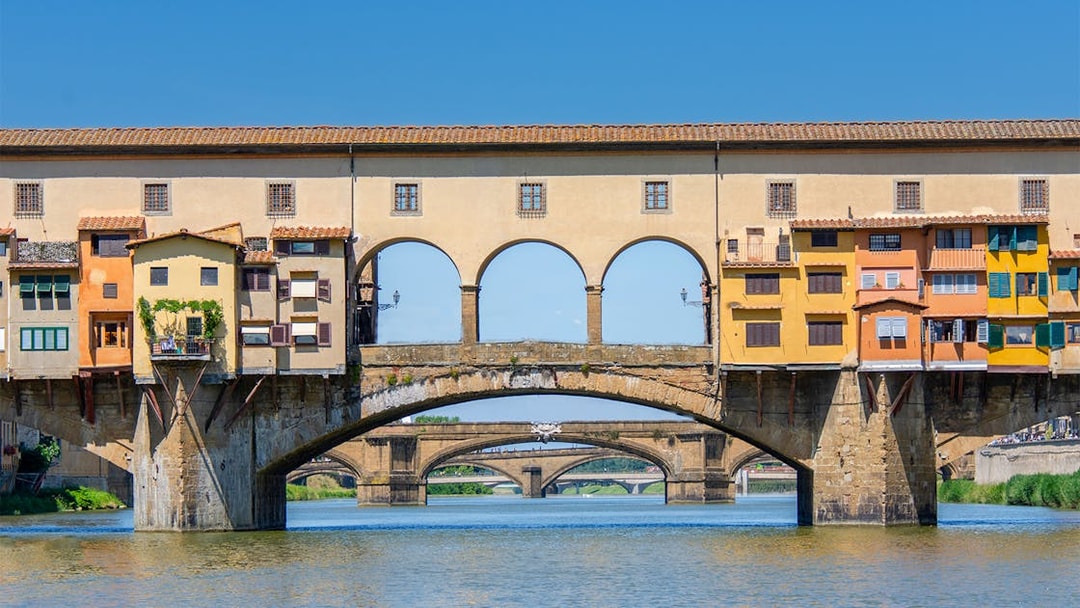 Florence tour bus crossing Ponte Vecchio bridge over the Arno River.