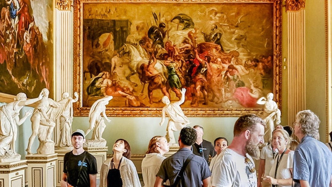 Visitors observing paintings and sculptures in the Rubens Niobe Room at Uffizi Gallery, Florence.