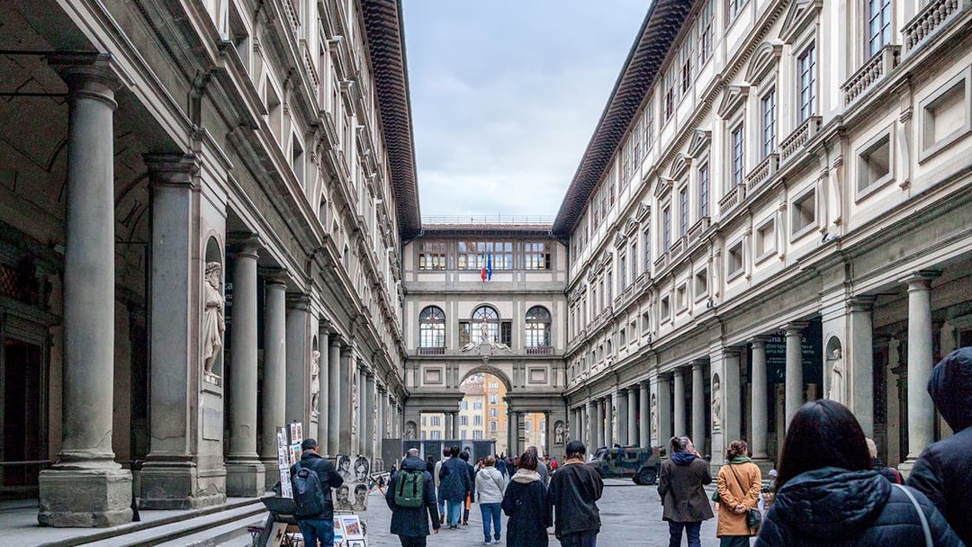 Uffizi Gallery courtyard in Florence with visitors walking through.