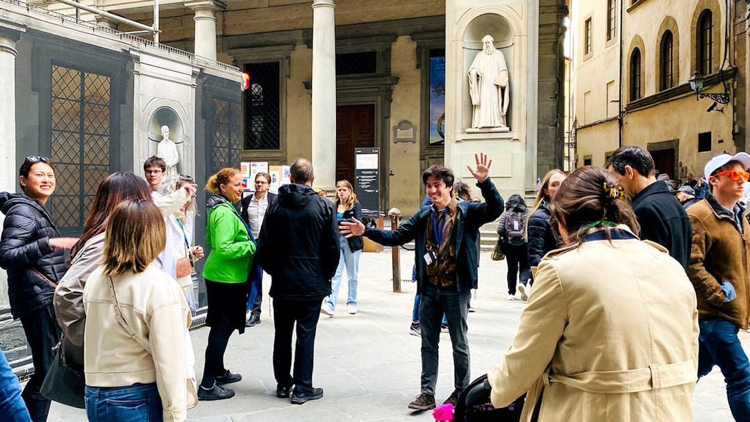 Tour group gathering outside Uffizi Gallery with guide in Florence, Italy.