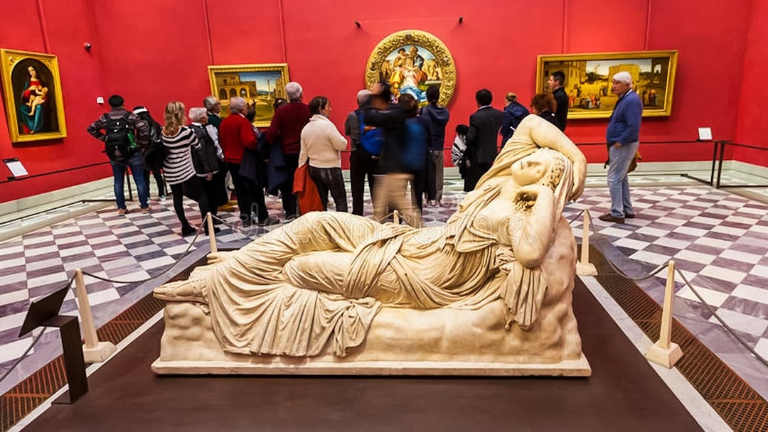 Reclining marble sculpture in Uffizi Gallery with visitors in red-walled room.