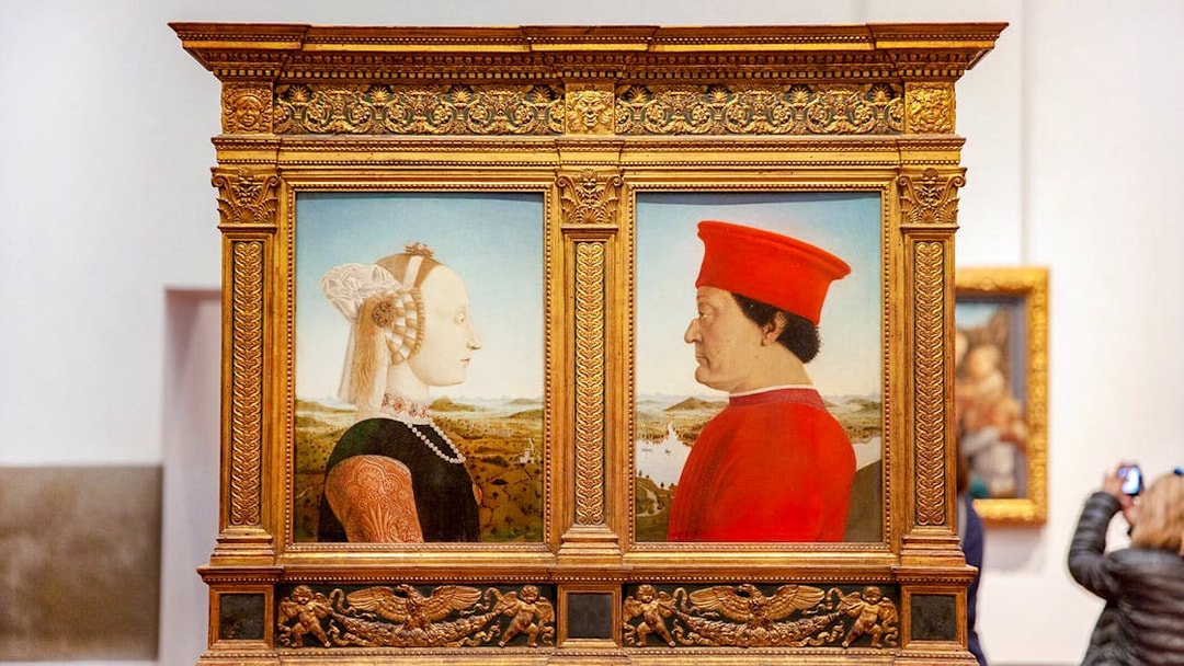 Portraits of a man and woman in ornate frames at Uffizi Gallery, Florence.