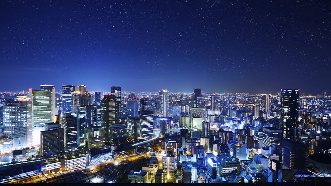 Night view of Osaka cityscape from Umeda Sky Building, illuminated buildings and starry sky.