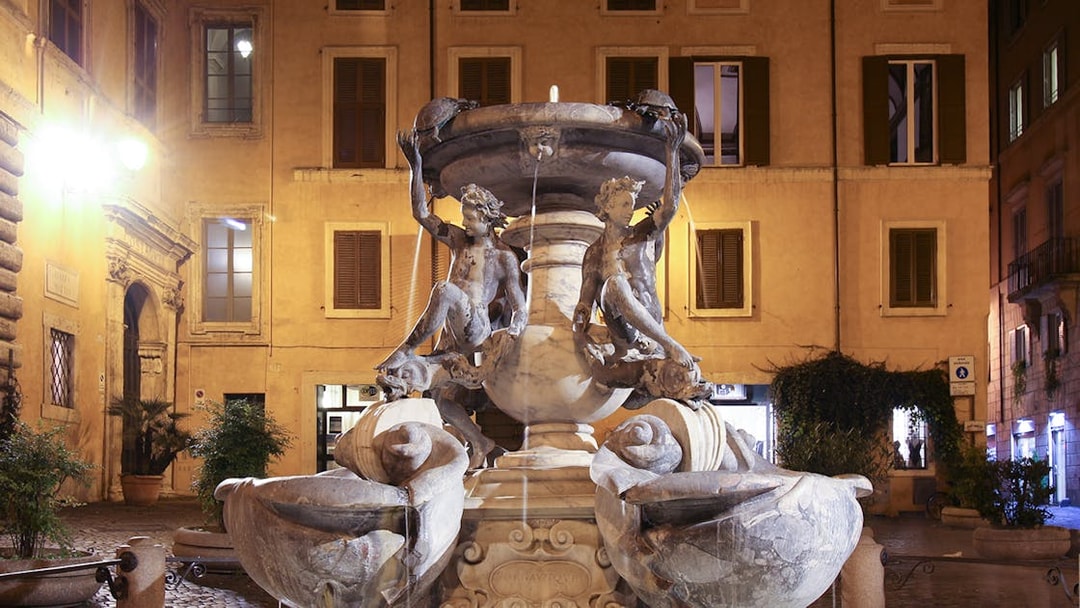 Turtle Fountain in Rome illuminated at night with sculptures and water features.