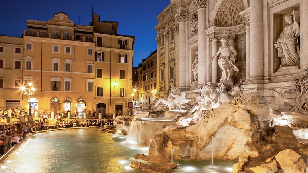 Trevi Fountain illuminated at night with surrounding buildings in Rome, Italy.