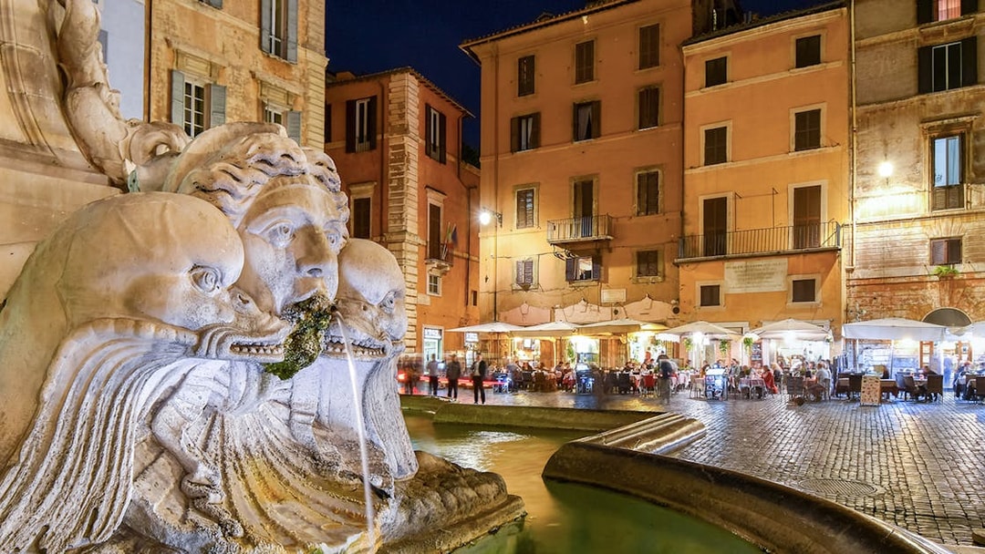Pantheon Fountain at night with illuminated cafes and shops in Piazza della Rotonda, Rome, Italy.