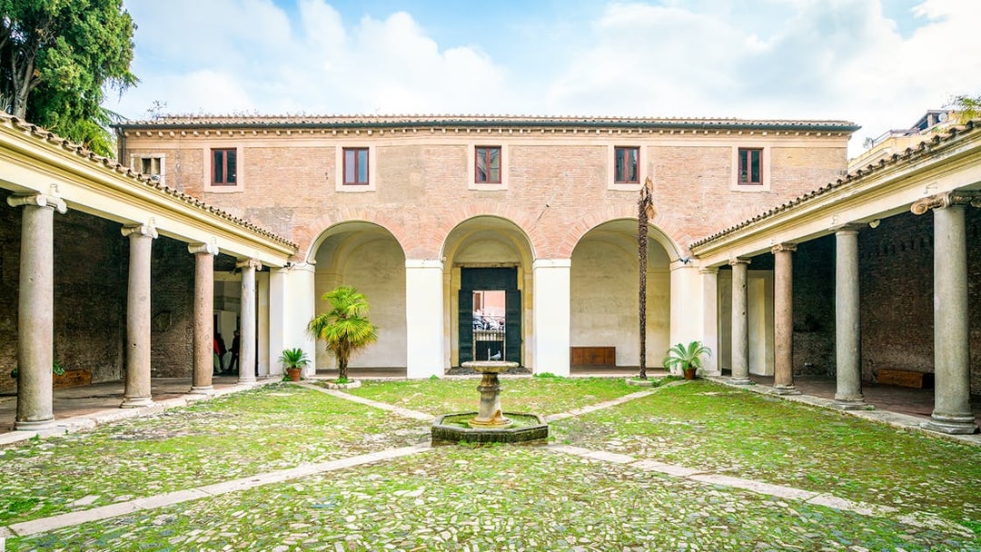 Courtyard of Basilica di San Clemente, Rome with columns and central fountain.