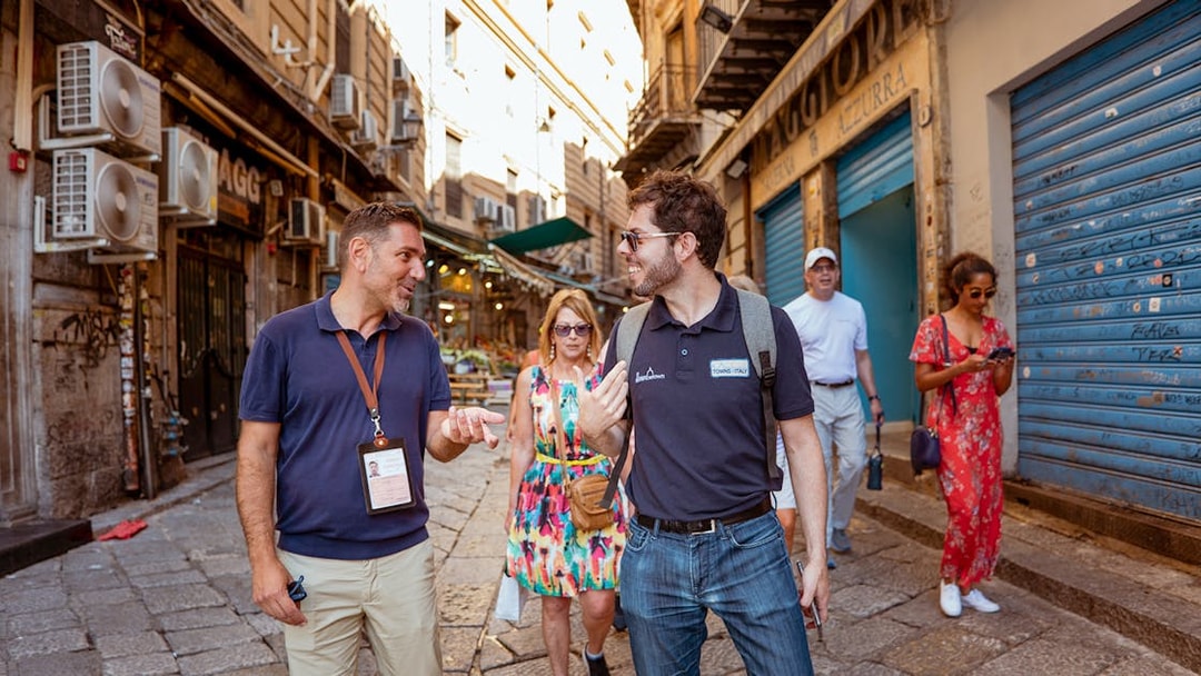 Tourists walking through a historic street in Palermo during a UNESCO Sites Walking Tour.