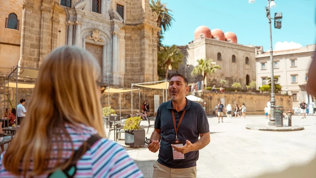 Tour guide leading a group in front of historic buildings in Palermo, Sicily.