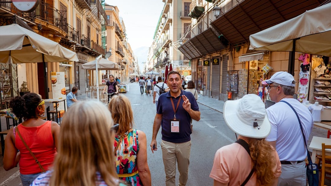 Tour guide leading a group through a historic street in Palermo, Italy.