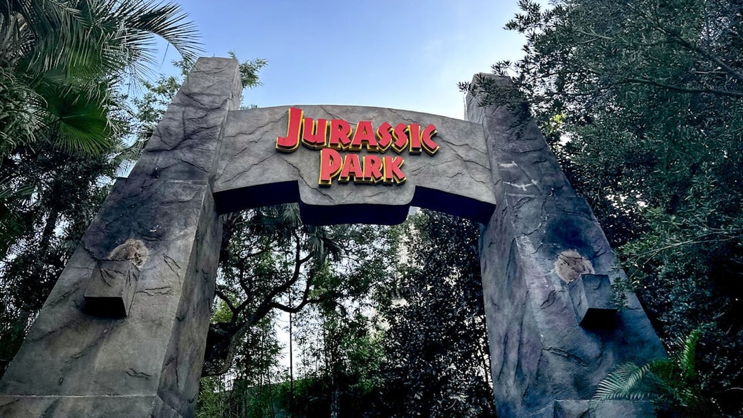 Jurassic Park entrance arch at Universal Orlando, Florida surrounded by lush greenery.
