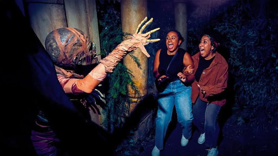 Guests react to a costumed performer at Universal Studios Hollywood Halloween Horror Nights.