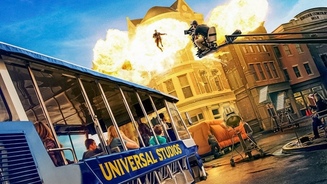 Universal Studios Hollywood tram tour with explosion and film crew on set.