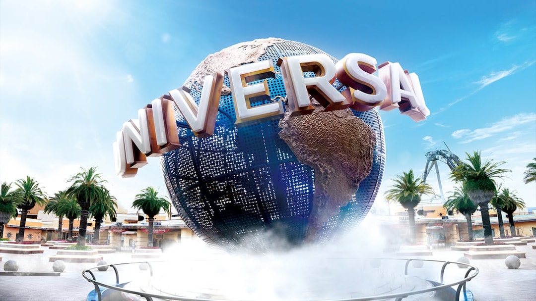 Universal Studios Japan globe with palm trees and clear sky.