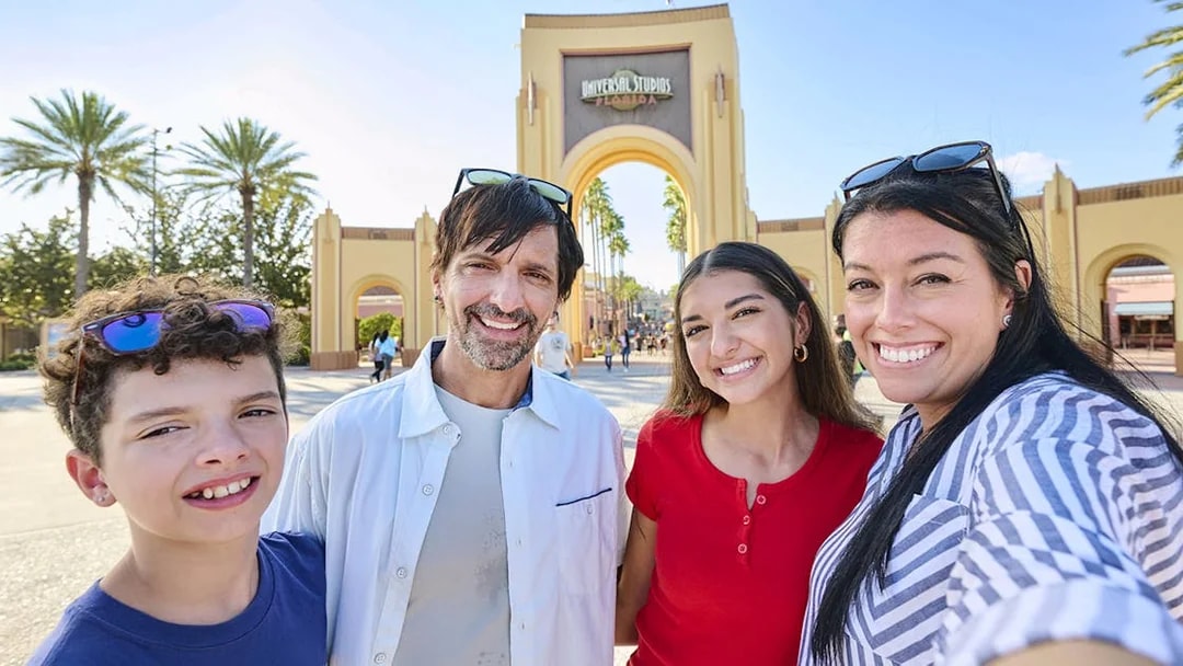 Guests smiling in front of Universal Studios Florida arch, Orlando.