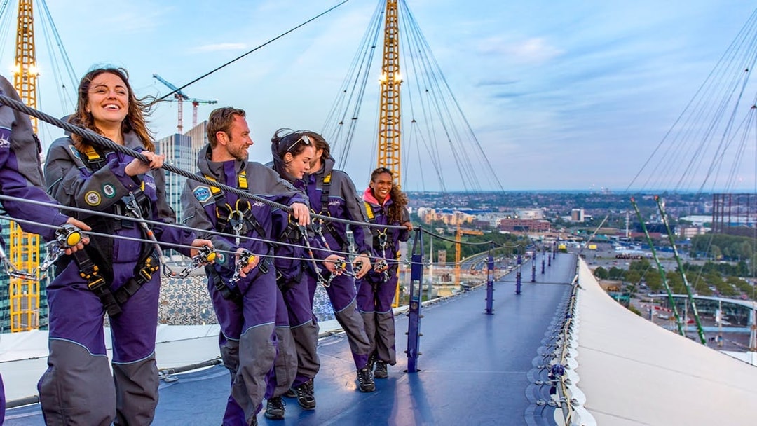 Guests climbing the O2 Arena roof at twilight in London.