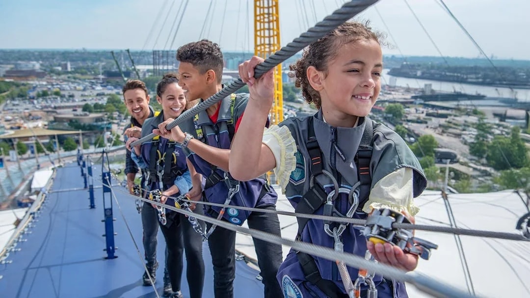 Guests climbing the O2 Arena roof in London during daytime.