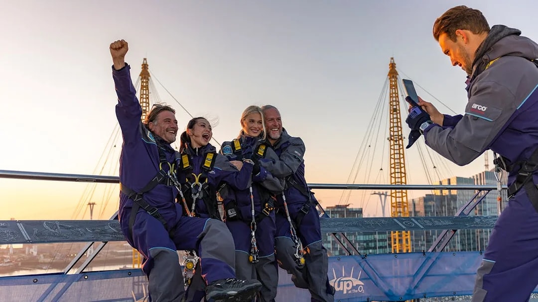 People celebrating on the O2 Arena roof at sunset during Up At The O2 adventure in London.