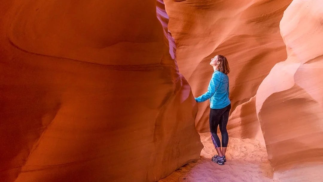 Young woman exploring the sandstone formations of Antelope Canyon, Arizona.