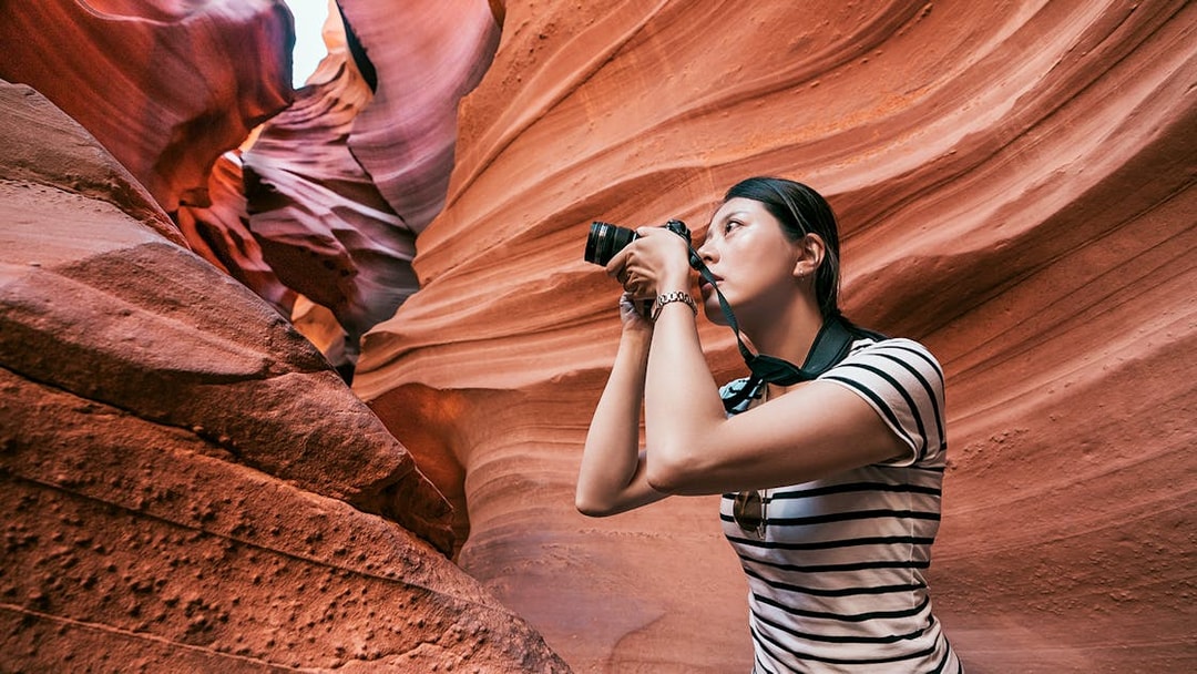Woman photographing sandstone formations in Upper Antelope Canyon, Arizona.
