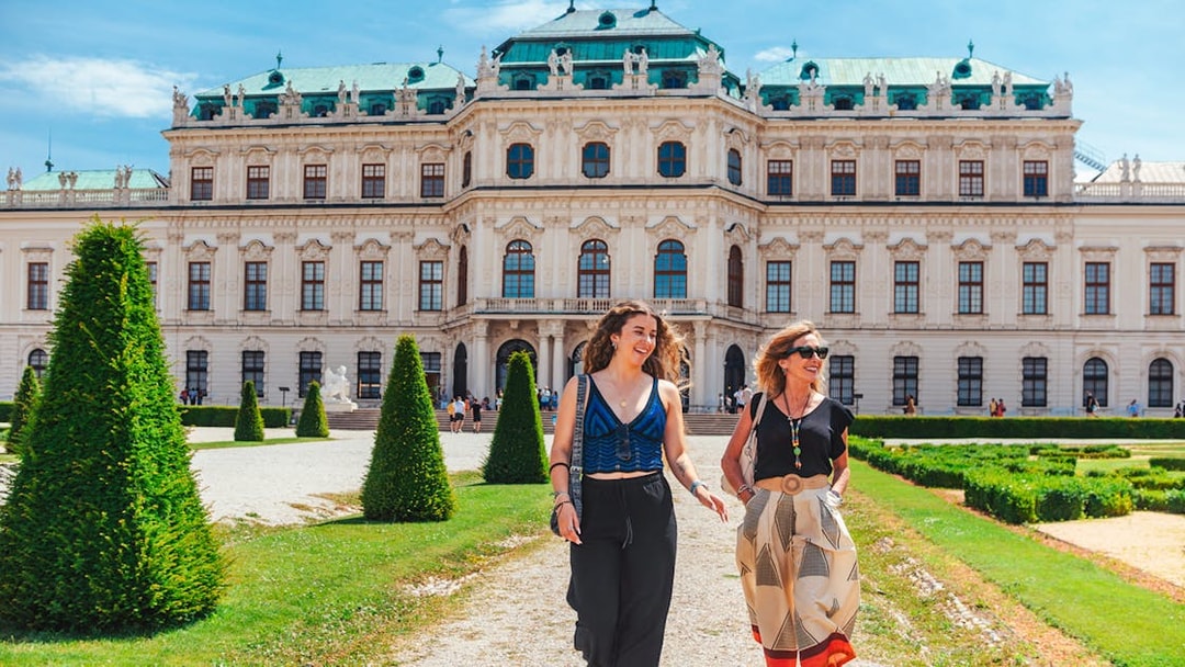 Tourists walking on the lawn of Upper Belvedere Palace in Vienna.