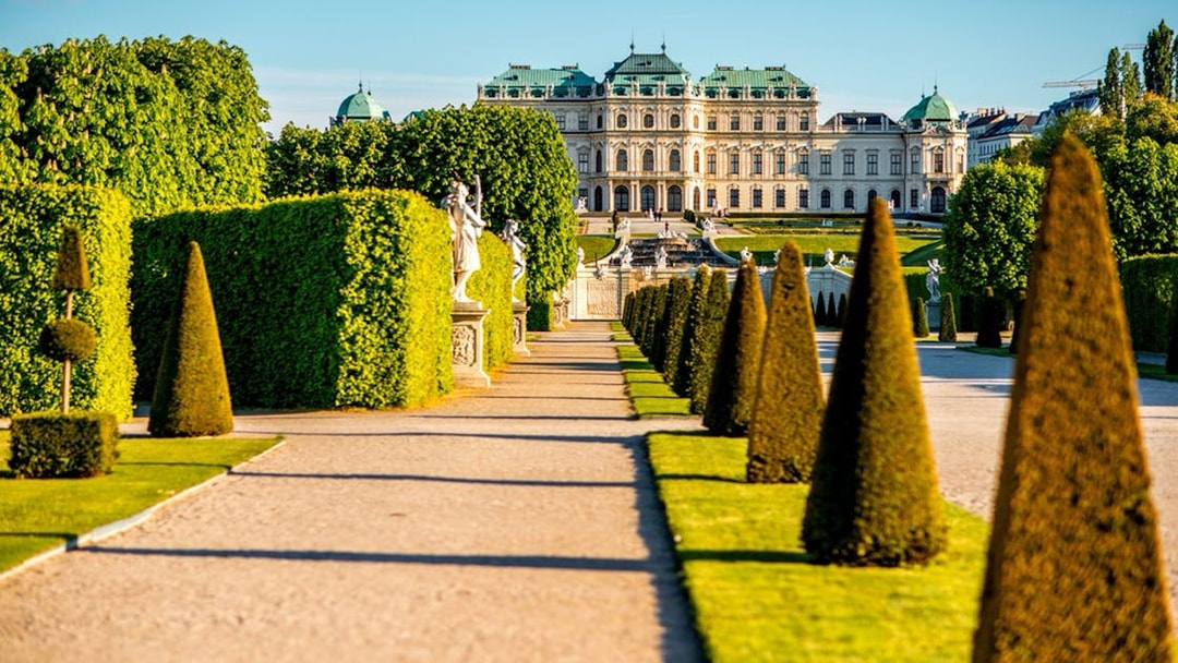 Upper Belvedere Palace gardens with statues and manicured hedges, Vienna.