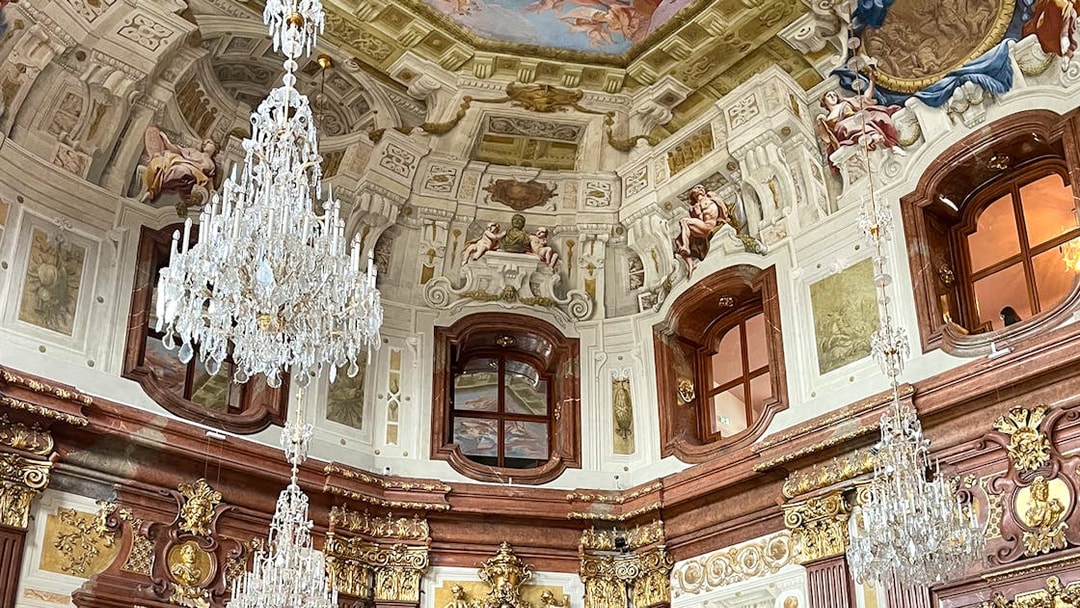 Marble hall interior with chandeliers and ornate ceiling in Belvedere Palace, Vienna.