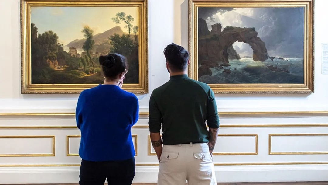 Visitors viewing landscape paintings in Belvedere Palace, Vienna.
