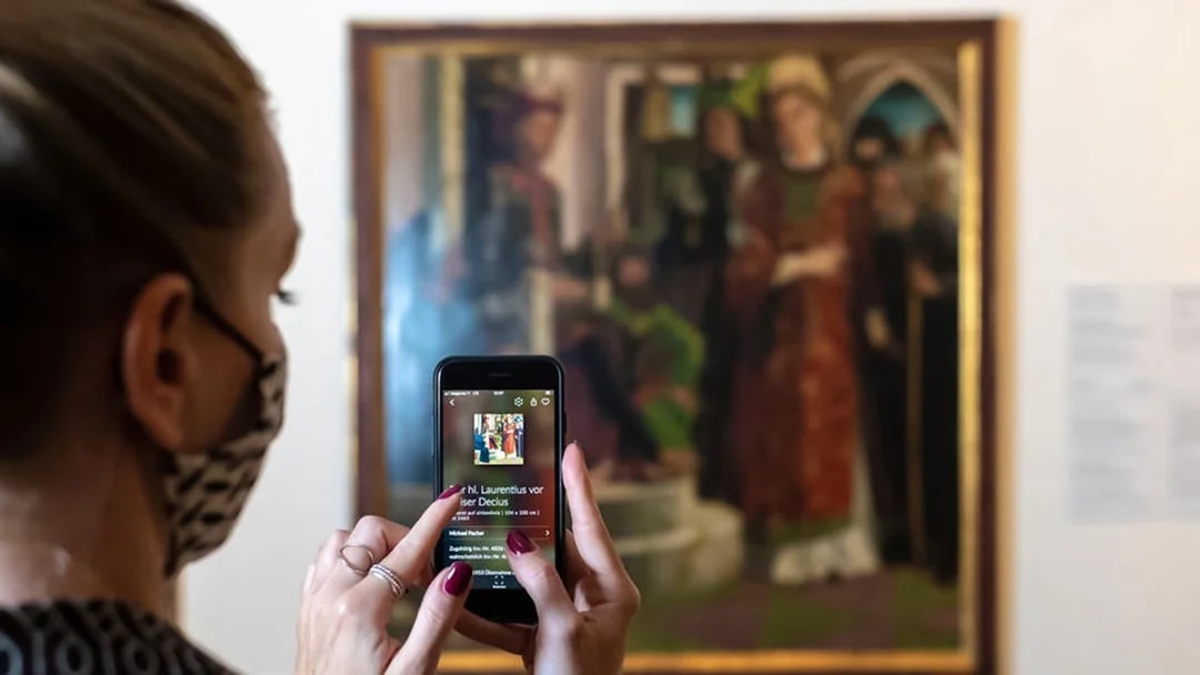 Visitor using a smartphone to view art details at Belvedere Palace, Vienna.