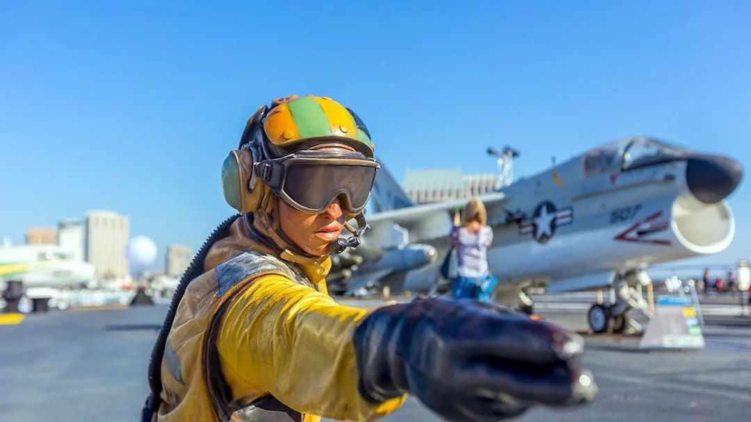 Aircraft carrier deck with crew member directing at USS Midway Museum, San Diego.
