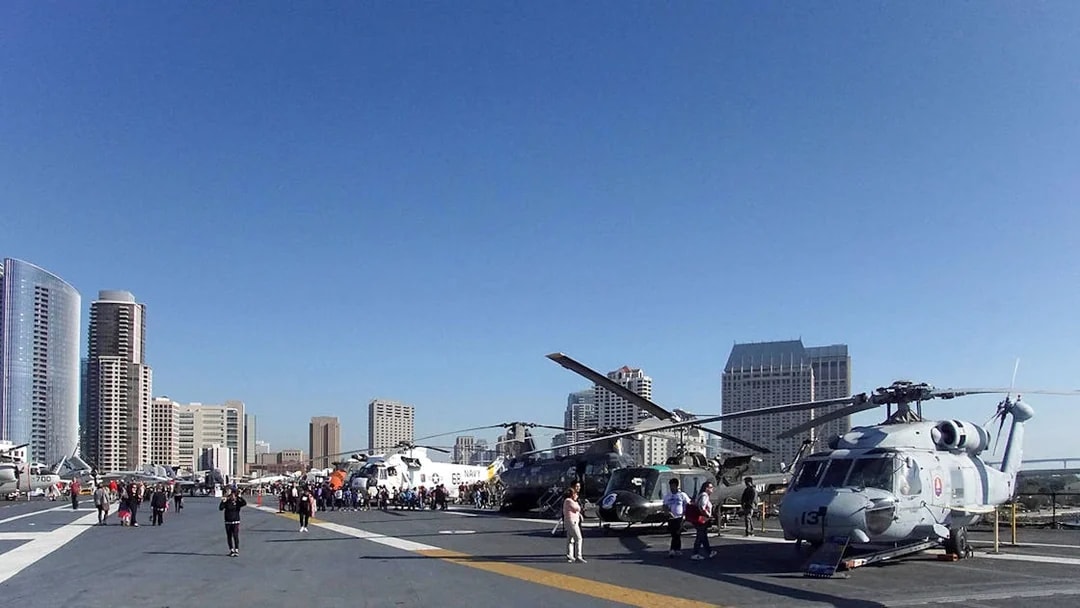 USS Midway Museum flight deck with helicopters and city skyline in San Diego.