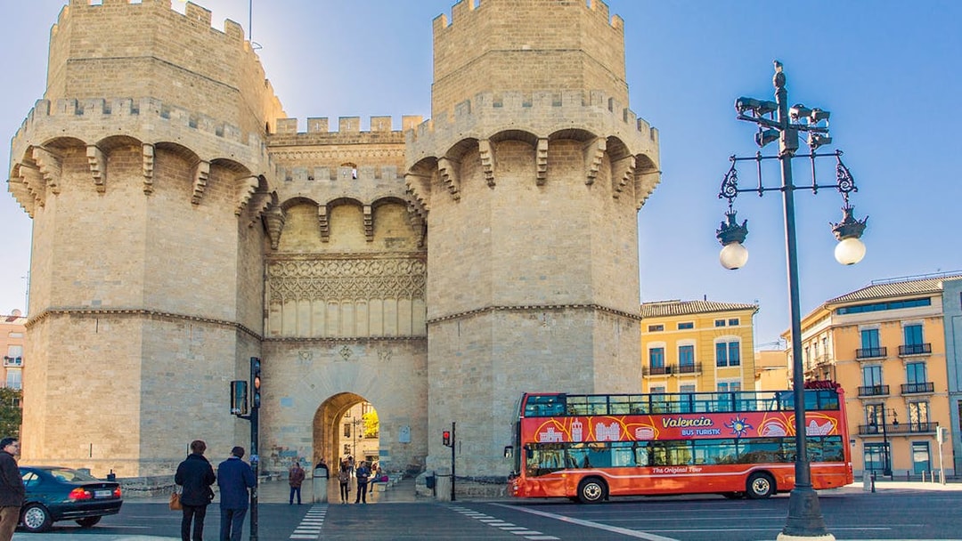 Valencia tour bus near Torres de Serranos with historic architecture.
