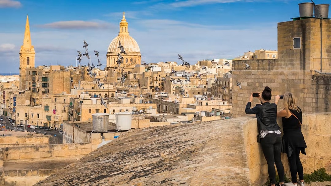Valletta skyline with St. Paul's Cathedral dome, tourists taking photos, Malta.