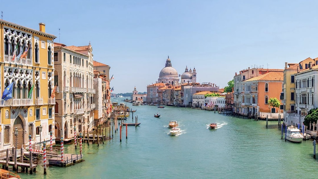 Water bus on Venice Grand Canal with historic buildings and Santa Maria della Salute in the background.