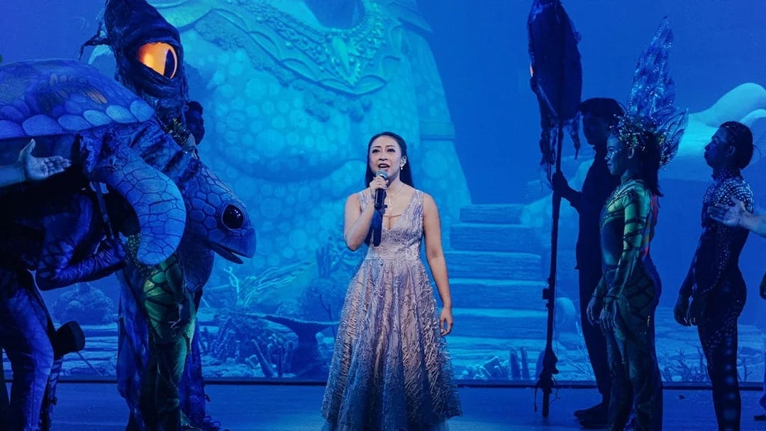Performer singing at Varuna, Underwater Theatrical Dining Experience with aquatic-themed costumes.