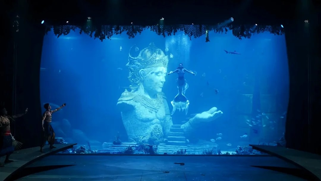Underwater performance with mermaid near Varuna statue in theatrical dining experience.