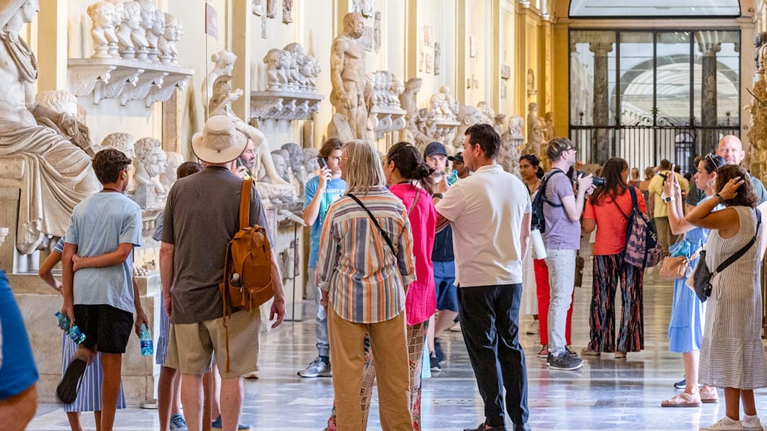 Visitors exploring sculptures on a guided tour of the Vatican Museums.