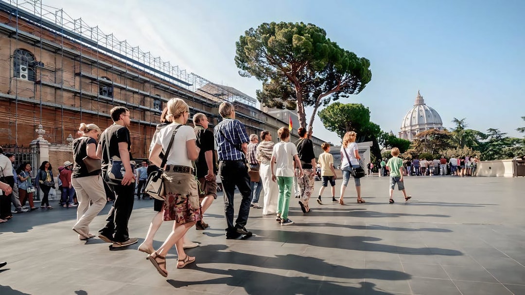 Visitors on a guided tour of Vatican Museums with St. Peter's Basilica in the background.