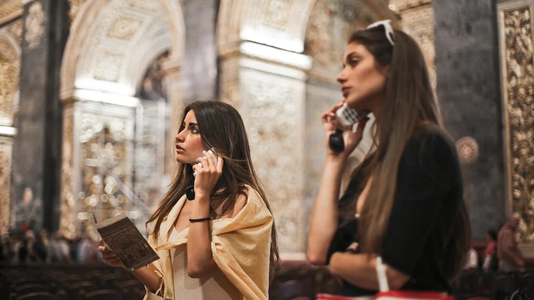 Tourists with audio guides exploring Vatican Museums' frescoes in Rome.