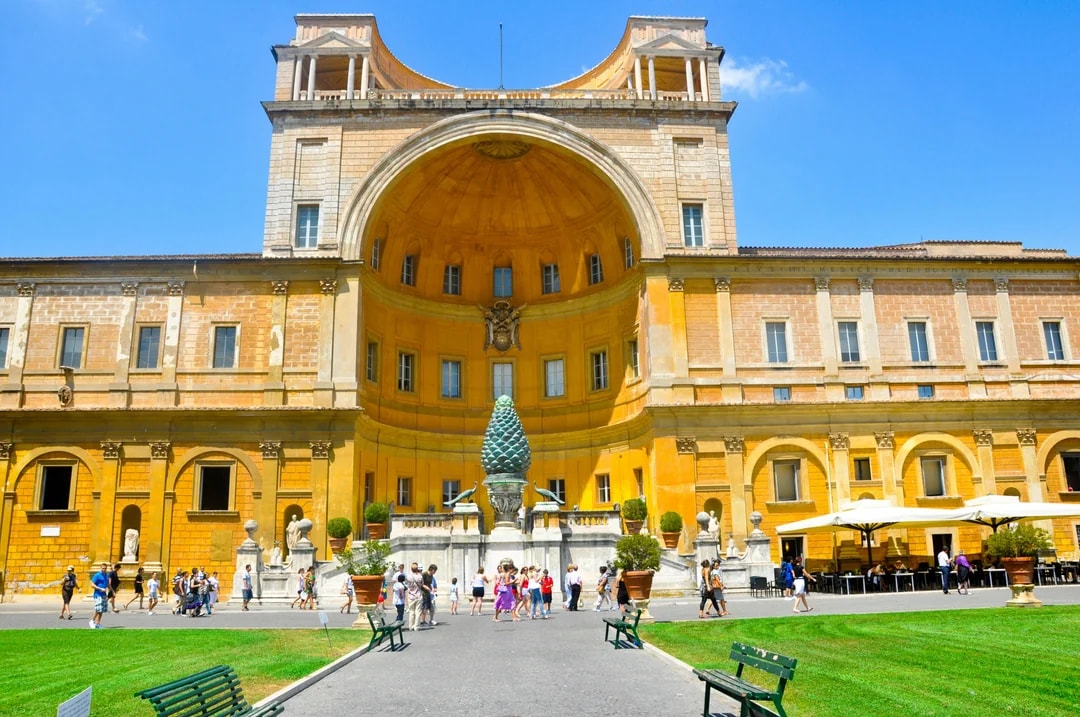 Vatican Museum courtyard with tourists in Rome, featuring the Pinecone sculpture.