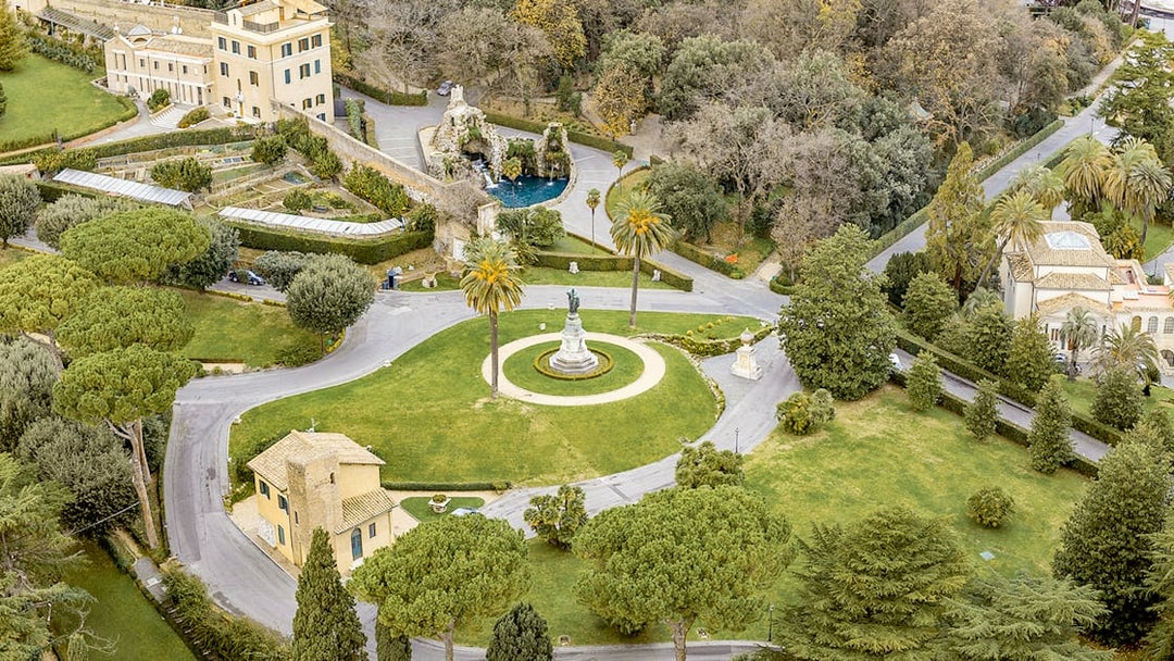 Aerial view of Vatican Gardens in Rome with pathways and a central statue.