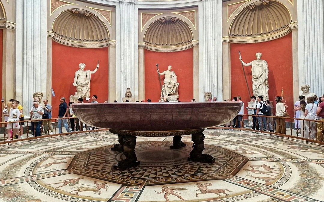 Sala Rotonda in the Vatican Museums with ancient statues and a large marble basin.