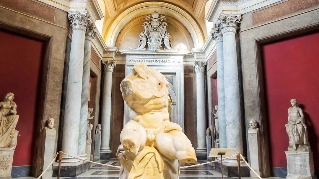 Vatican Museums sculpture hall with ancient statues and marble columns.