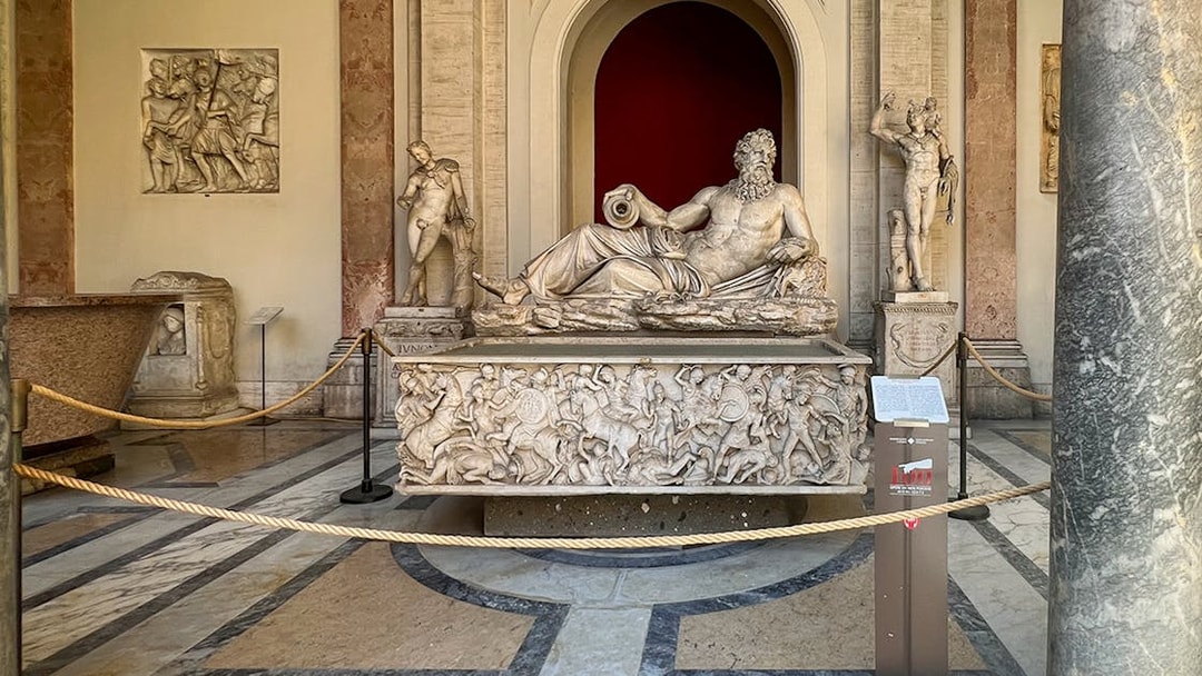 Marble statue of River God Arno at Vatican Museums, surrounded by detailed carvings.